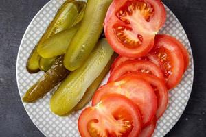 pepino y tomate en escabeche en un plato. foto