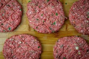 carne cruda preparada para hamburguesas. carne sazonada en una tabla de madera. vista superior. foto