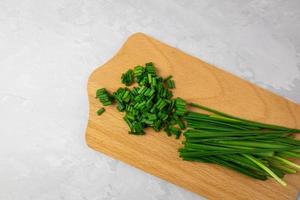 Chopped chives lying on a wooden board. Top view.