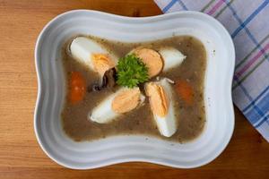 Pule la sopa de centeno agrio con huevo en un tazón blanco. vista superior. foto