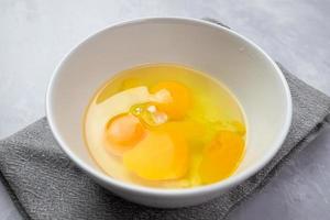 Raw eggs in a white bowl. Preparation of ingredients for cooking.