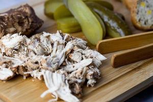 Pulled chicken with bread and pickled cucumber.