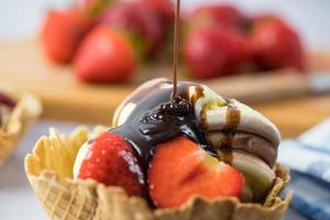 Postre helado con fresas y chocolate vertido foto