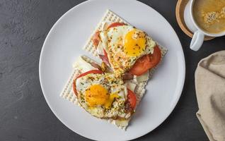 Diet bread sandwiches with egg and juicy tomato on a white plate. View from above. photo