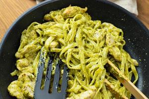 Pasta with pieces of chicken and basil pesto prepared in a pan. photo