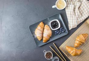 Croissants with powdered sugar and blueberries on a black plate. Top view with space for text. photo