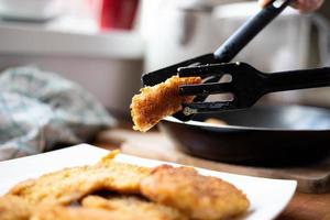 Fried pieces of breaded chicken. Preparation of a traditional dinner.