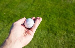 Pelota de golf sostenida en la mano en el campo de golf concepto de golf foto