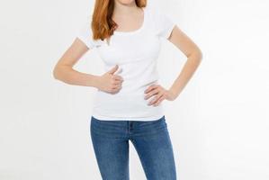 Hermosa chica de pelo rojo muestra como signo en una camiseta blanca aislada. Sonrisa bonita mujer de cabeza roja en camiseta maqueta, en blanco. foto