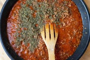 salsa de tomate con carne de res, calentada en una sartén. vista desde arriba. preparación de comida italiana. foto