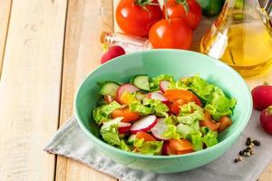 Fresh vegetable salad with olive oil in ceramic bowl on wooden background. photo