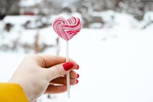 Hand holds pink lollipop. photo