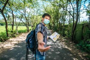 los turistas masculinos se paran y miran el mapa en la carretera. foto