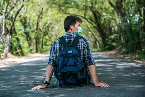 Male tourists wearing a mask, carrying a backpack on the road photo