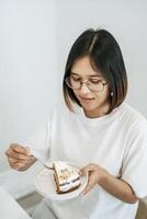 The girl eats cake and has a laptop on the table. photo