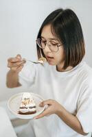 The girl eats cake and has a laptop on the table. photo