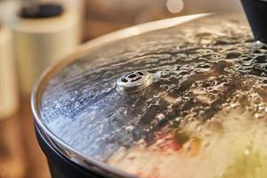 Frying pan lid with drops and steam close-up, in the kitchen photo