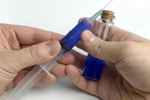 Hand holding test tube with blue liquid and a syringe. photo