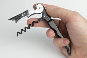 The hand holding the corkscrew on white background for wine bottles.
