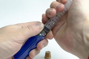 Hand holding test tube with blue liquid and a syringe. photo