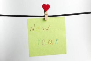 el papel pesa sobre la cuerda negra con las palabras feliz año nuevo. foto