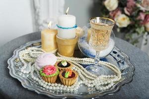 Candles, cake, pearls on a silver tray. photo