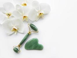 Rodillos de jade de masaje facial sobre fondo blanco. foto