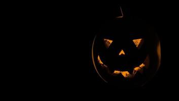 Pumpkin for Halloween glowing demon face in dark. Scary Halloween pumpkin face photo