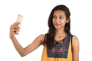 Retrato de una niña feliz mediante teléfono móvil aislado sobre fondo blanco. foto