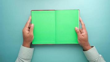Vista superior de la mano del hombre sujetando el bloc de notas con páginas verdes video