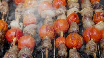 Cinemagraph of smoke emitted from cooking chicken hearts with tomato and onion on a hot BBQ grill video