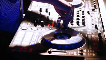 Las manos de DJ modifican varios controles de pista en la consola mezcladora de DJ en la discoteca video