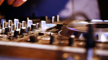 mãos do dj ajustam vários controles de faixa no console do dj mixer na boate video