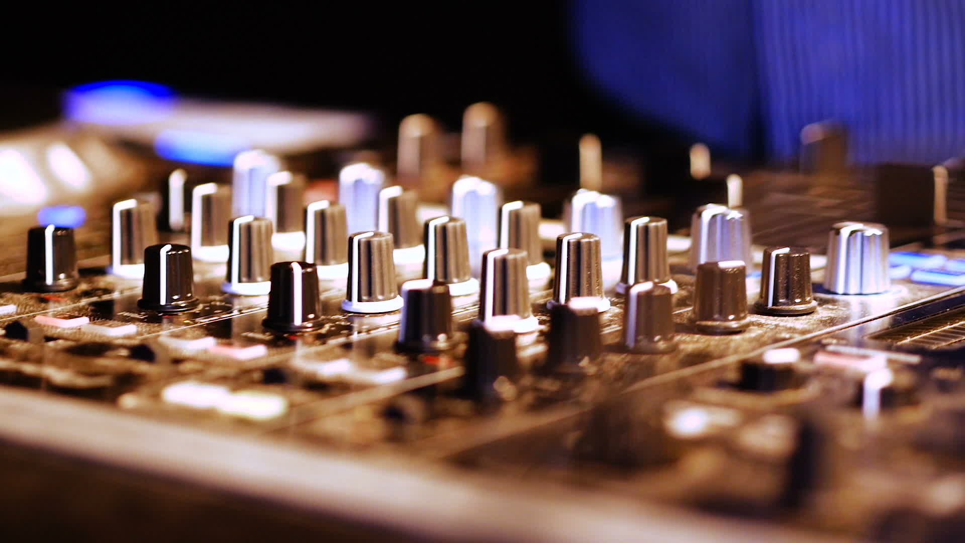 Hands of DJ tweak various track controls on DJ mixer console at ...