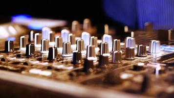 mãos do dj ajustam vários controles de faixa no console do dj mixer na boate video