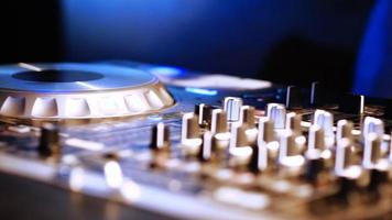 Hands of DJ tweak various track controls on DJ mixer console at nightclub video