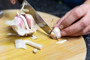 preparación de piezas de ajo para exprimir. ajo acostado sobre una mesa de madera. foto