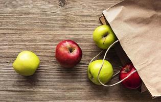 Fresh apples in a paper bag on a wooden background photo