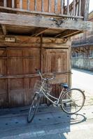 la bicicleta de estilo antiguo está estacionada. al lado del antiguo edificio de madera hay sol en la tarde del día. foto