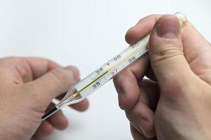 Hand holds a thermometer.