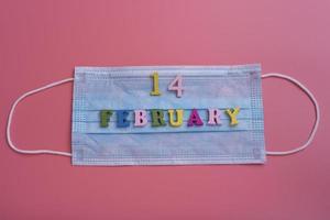 February 14 on a medical mask and pink background. photo