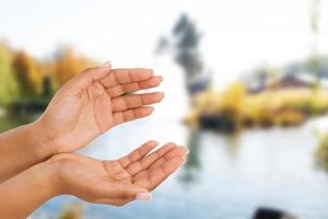 black female hand two palm up, handbreadth isolated on blurred river background. Front view. Mock up. Copy space photo
