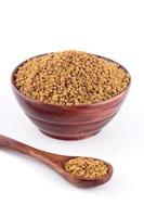 Fenugreek seeds in wooden bowl with spoon isolated on white background photo