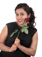 Beautiful young girl or woman holding and posing with red rose flower on white background photo