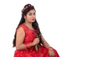 Beautiful young girl or woman holding and posing with red rose flower on white background photo