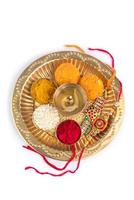 festival indio rakhi con granos de arroz, kumkum, dulces y diya en un plato con un elegante rakhi. una pulsera tradicional india que es un símbolo del amor entre hermanos y hermanas foto