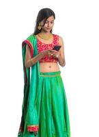 Young Indian traditional girl using a mobile phone or smartphone isolated on a white background photo