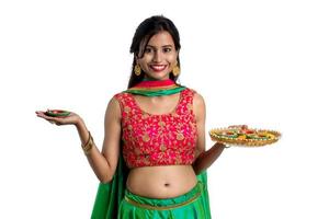 Portrait of a Indian Traditional Girl holding Diya, Girl Celebrating Diwali or Deepavali with holding oil lamp during festival of light on white background photo