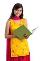 Pretty young girl holding book and posing on white background photo