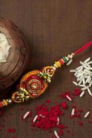 Indian festival Raksha Bandhan background with an elegant Rakhi, Rice Grains and Kumkum. A traditional Indian wrist band which is a symbol of love between Brothers and Sisters. photo